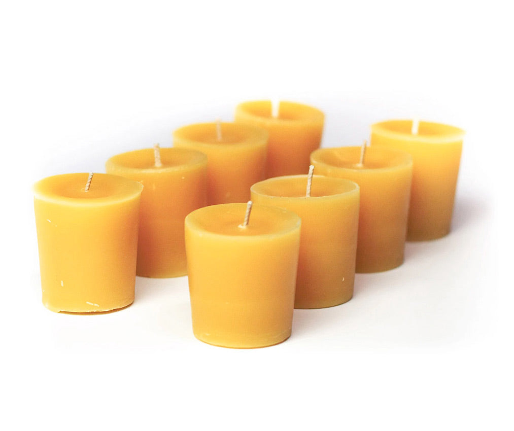 A group of yellow beeswax votive candles arranged on a white surface