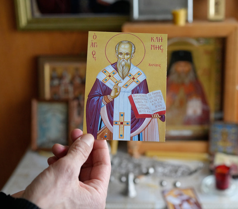 Icon of St. Clement of Ohrid holding a book, with a halo and a golden yellow background.