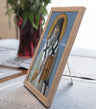 Framed religious icon of a saint on a table with a plant in the background