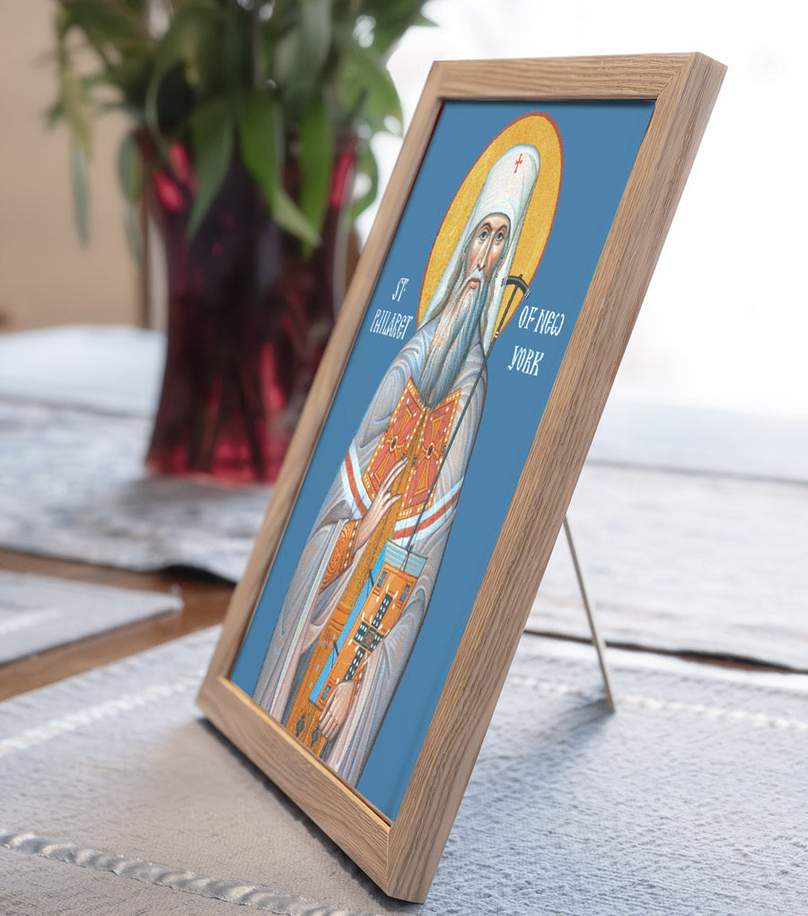 Framed religious icon of a saint on a table with a plant in the background