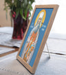 Framed religious icon of a saint on a table with a plant in the background