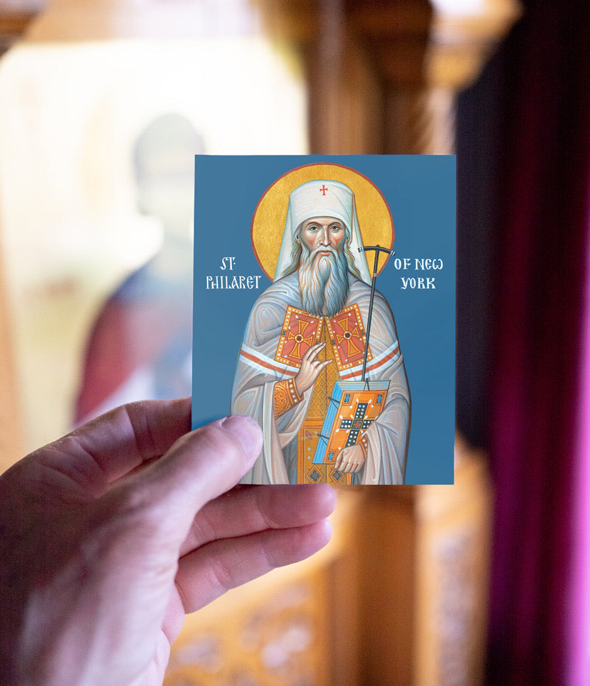 Card with a religious icon of a saint held by a hand against a blurred background