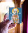 Card with a religious icon of a saint held by a hand against a blurred background
