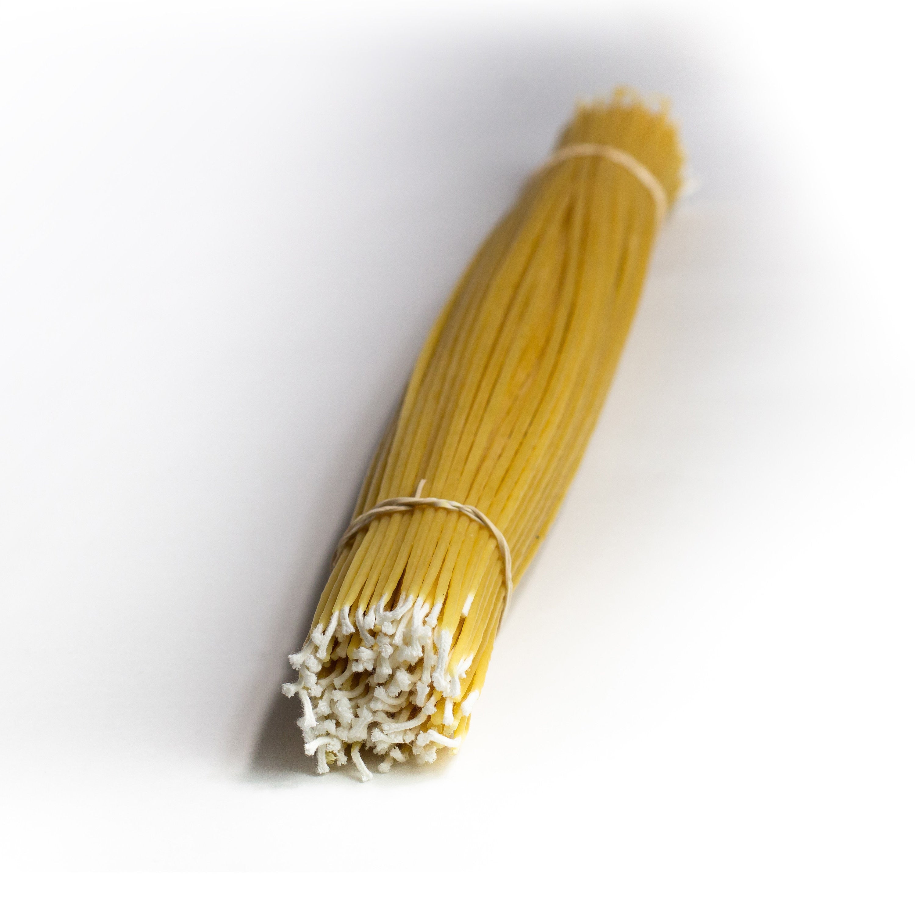 A bundle of light beige colored wax taper candles bound together, with an elastic band.