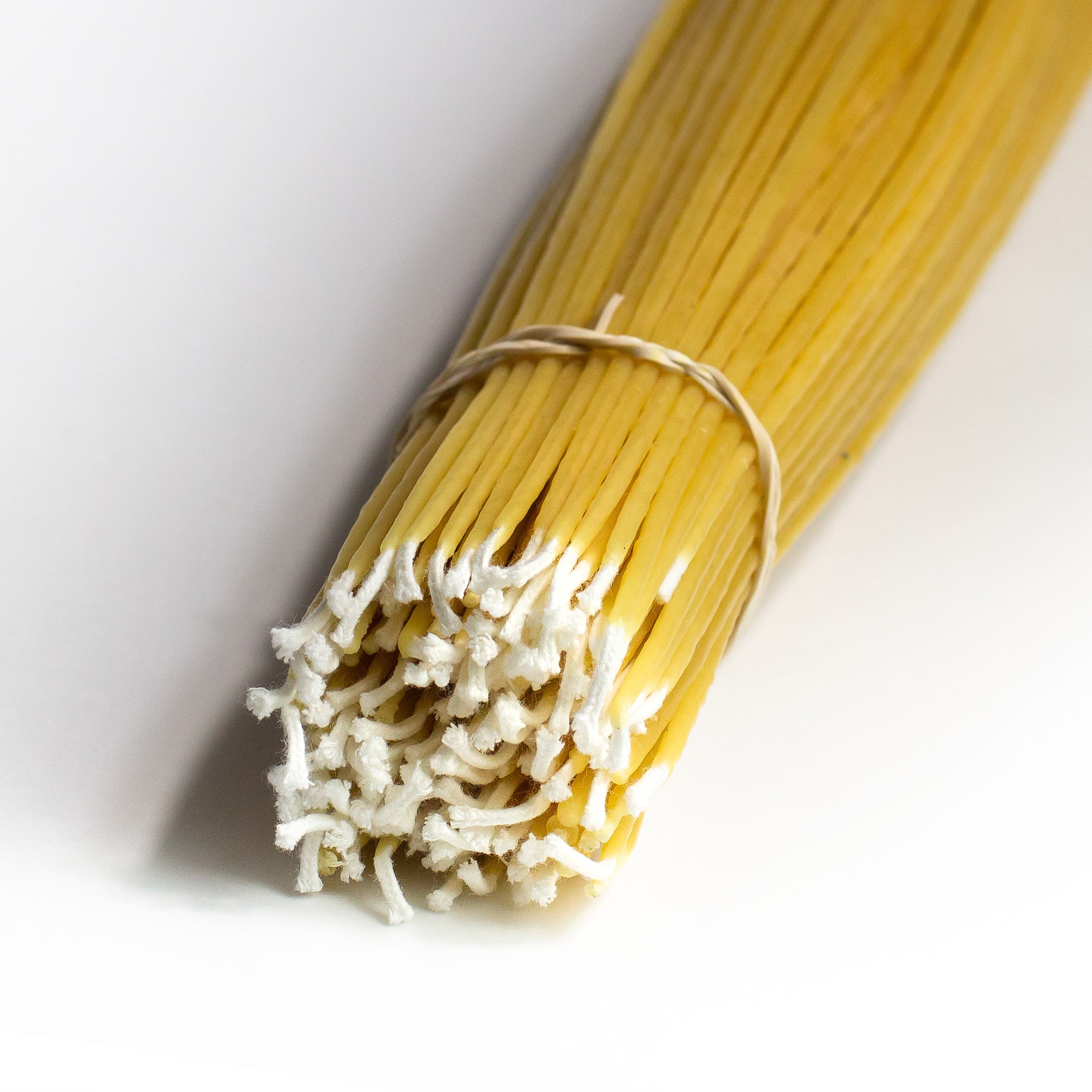 A bundle of light beige colored wax taper candles bound together, with an elastic band.