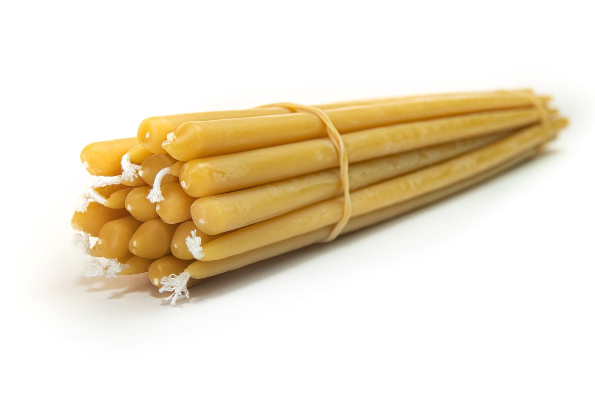 A bundle of yellow beeswax taper candles tied together.